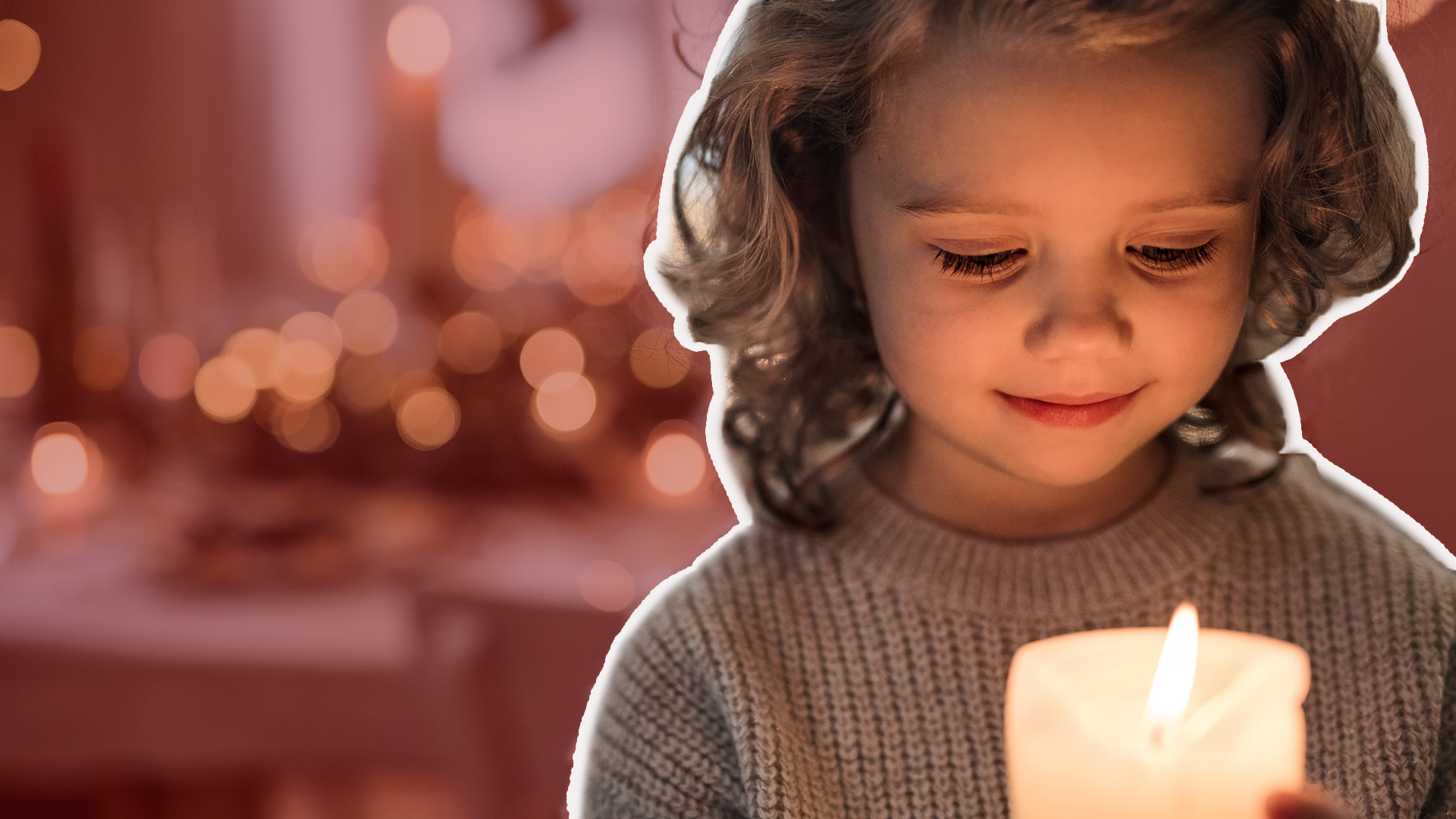 Young child holds a lit candle with christmas decorations in the background